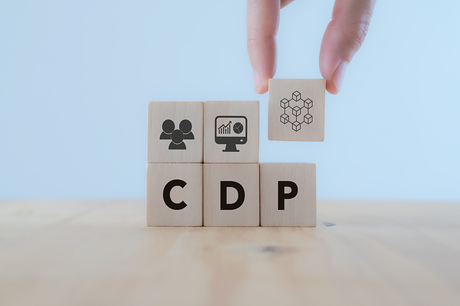 Customer Data Platform (CDP) concept. Marketing tool benefit for online business. Data planning for customer database mangement and accessible to other systems. Hand puts wooden cube with CDP icon.